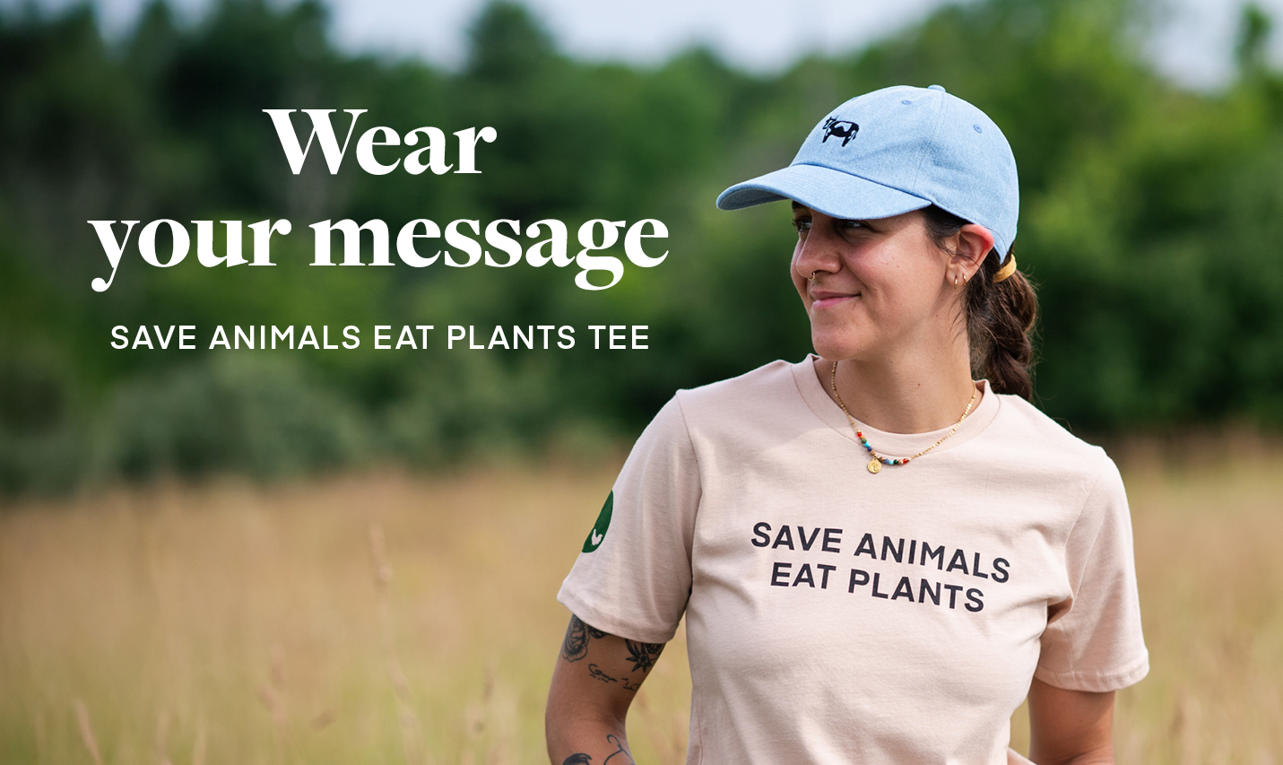 Woman wearing our Save Animals Eat Plants Tee and Embroidered cow hat. Text: Wear your message. Shop our Save Animals Eat Plants T-shirt.